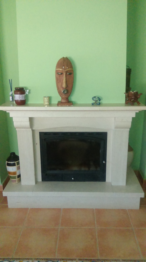 Chimenea de leña cerrada con cristal y mármol travertino.