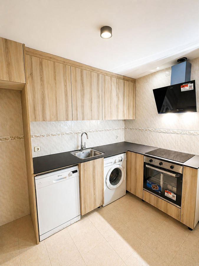 Cocina moderna en L con acabado efecto madera y encimera negra