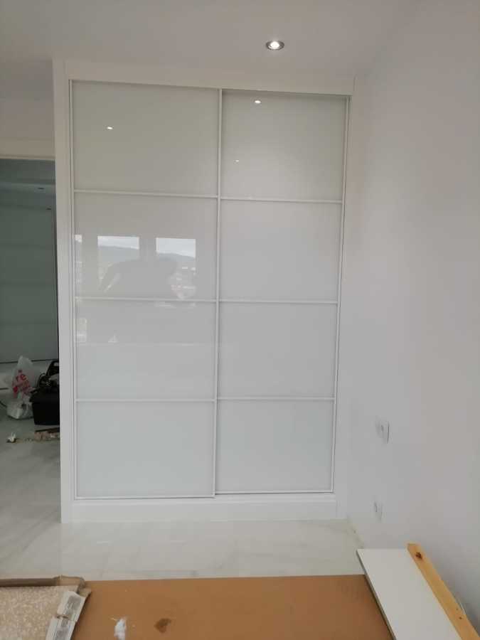 Armario empotrado con perfileria blanca minimalista y vidrios lacobel blanco .