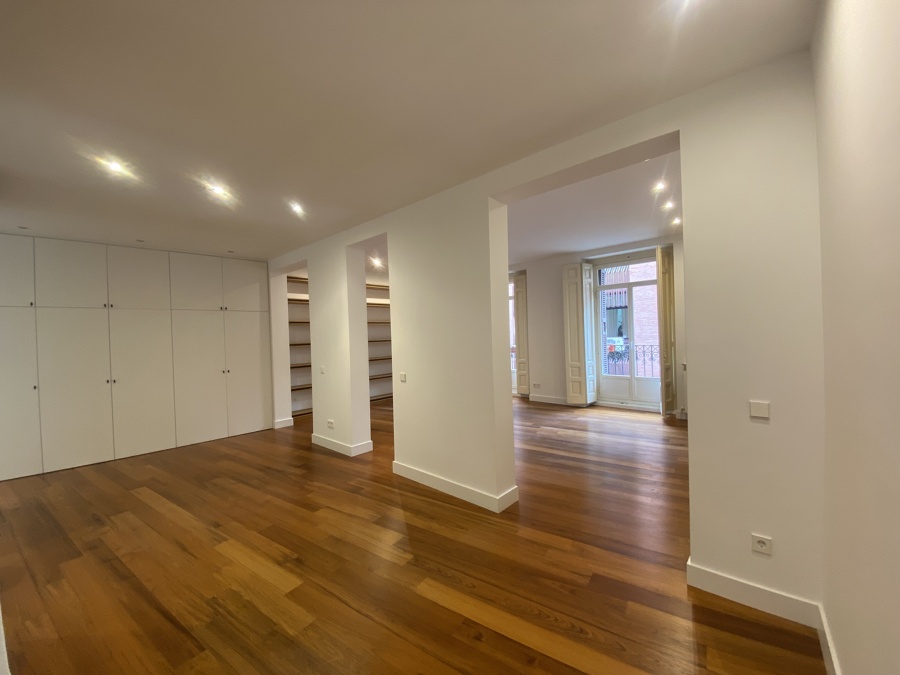 Reforma integral de piso en el centro de Madrid: salón diáfano con tarima restaurada y balcón original