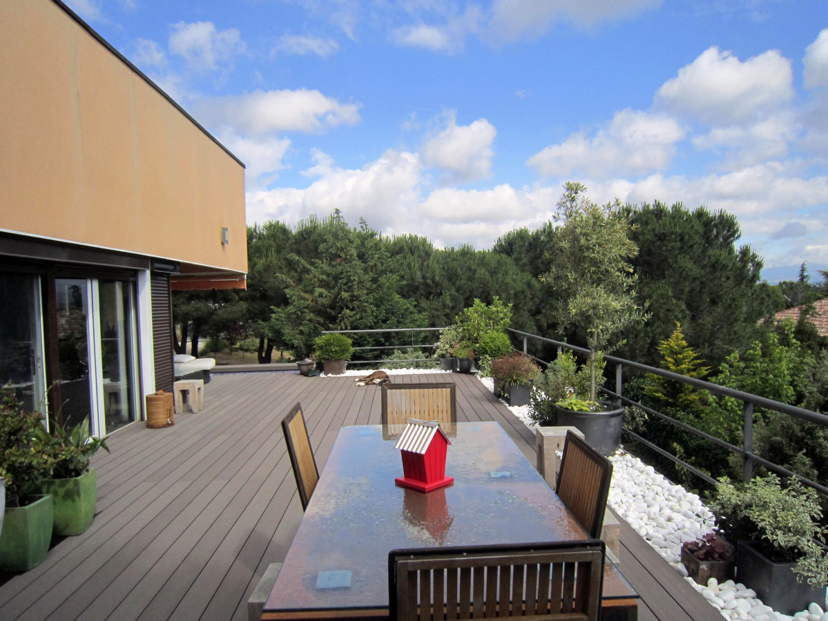 Terraza con suelo técnico bordeada con bolos y macetas