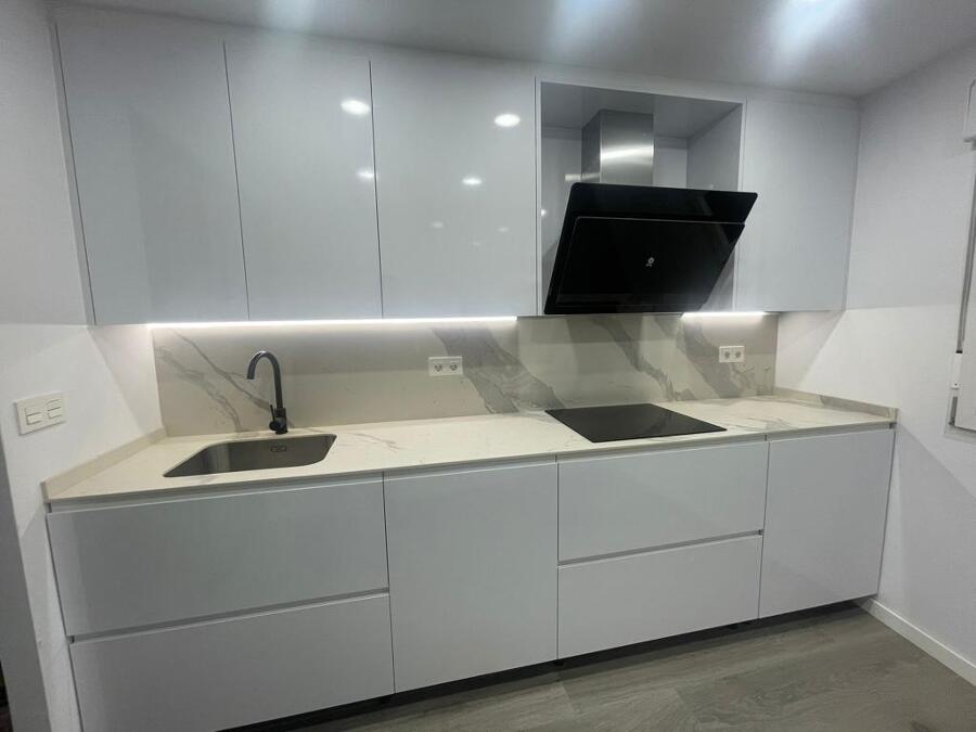 Cocina blanca con encimera y frente porcelánicos efecto mármol