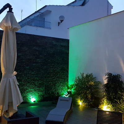 Patio con muro llorón iluminado con mobiliario de jardín