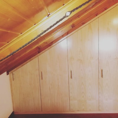 Armario empotrado con puertas en rechapado de pino barnizado .
