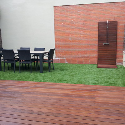 Jardín con césped artificial, madera tropical y ducha de jardín