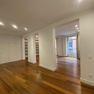 Reforma integral de piso en el centro de Madrid: salón diáfano con tarima restaurada y balcón original
