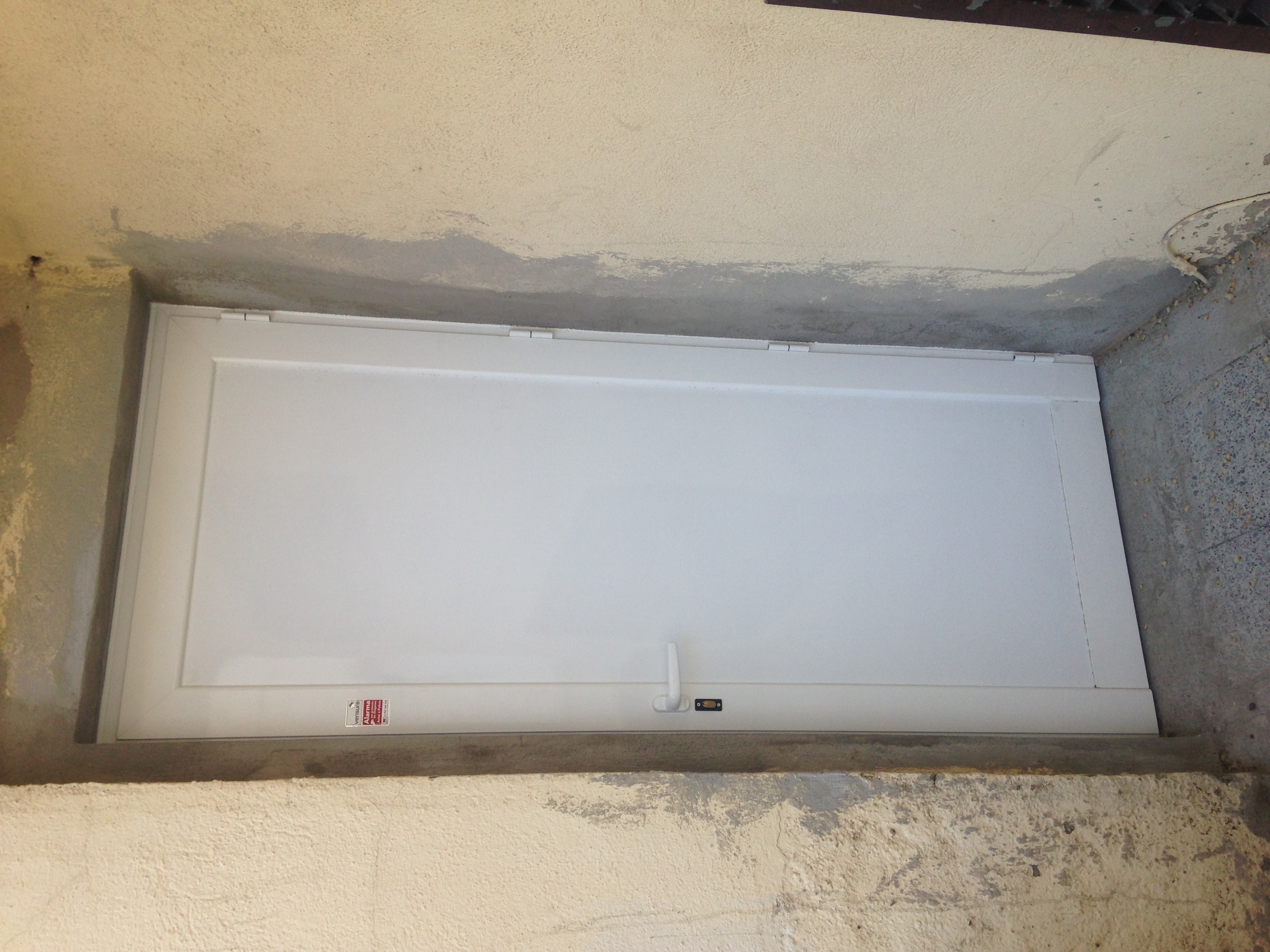 Puerta E.E.B. Primera de Sabadell de aluminio blanco serire Alba ciega, con cerradura y freno.