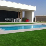 Construcción de piscina desbordante con cesped artificial modelo DIAMANTE en su perímetro