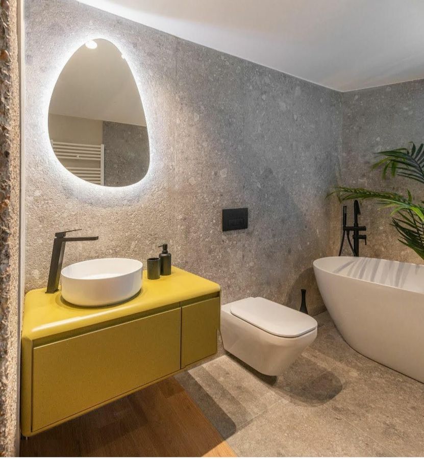 espejo de baño retroiluminado con forma ovalada en baño moderno con bañera exenta