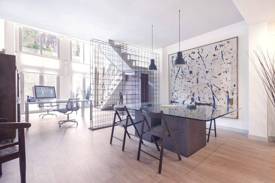 Zona de reuniones abierta con mesa de cristal y separación conceptual