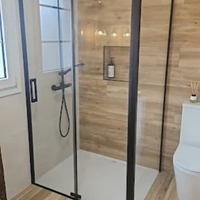 Cambio de bañera por plato de ducha con revestimiento efecto madera y mampara negra