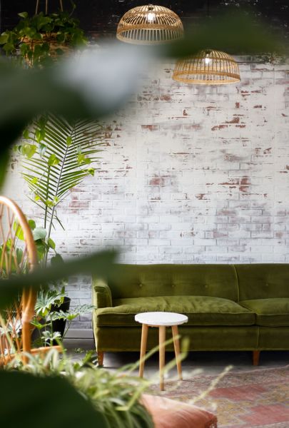 Salón de estilo tropical con sofá verde