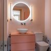 Baño rosa con espejo redondo