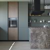 Cocina en verde y piedra con gran campana extractora