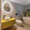 espejo de baño retroiluminado con forma ovalada en baño moderno con bañera exenta