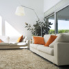 Salón con sofás y paredes blancos, y textiles en naranja